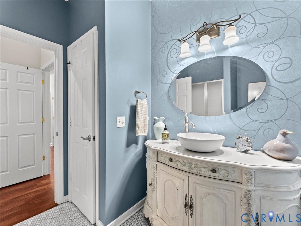 4105 English Holly Circle, Glen Allen, VA 23294 Bathroom vanity featuring a distressed white finish, countertop vessel sink, oval mirror, three-light fixture, and mosaic tile flooring