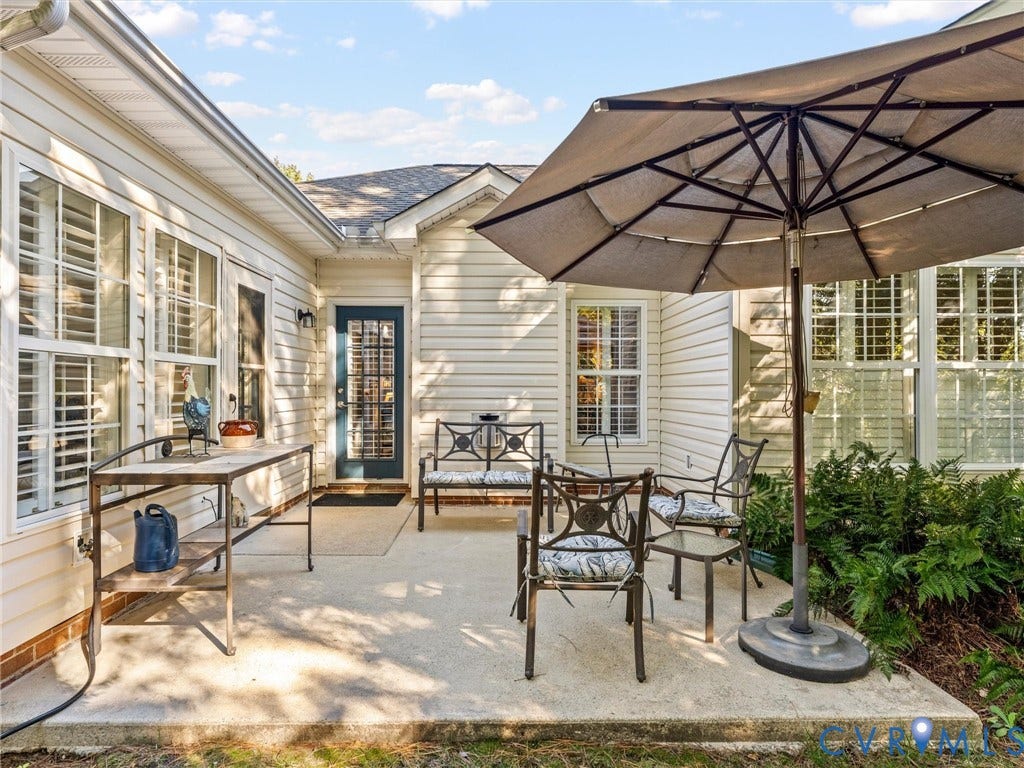 4105 English Holly Circle, Glen Allen, VA 23294 Concrete patio featuring light-colored horizontal siding, glass-paneled exterior door, and multi-pane windows