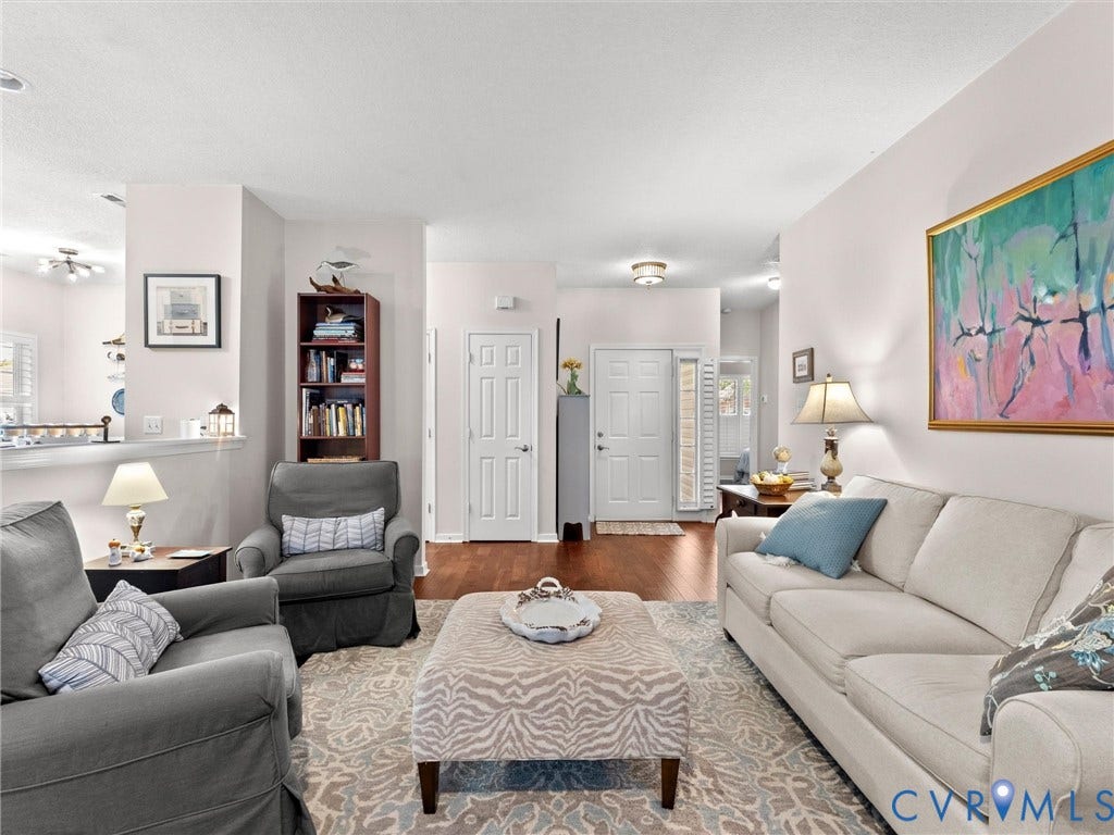 4105 English Holly Circle, Glen Allen, VA 23294 Open-concept living space featuring wood-finish flooring, neutral wall paint, a built-in recessed bookshelf, and a six-panel entry door with a side window light