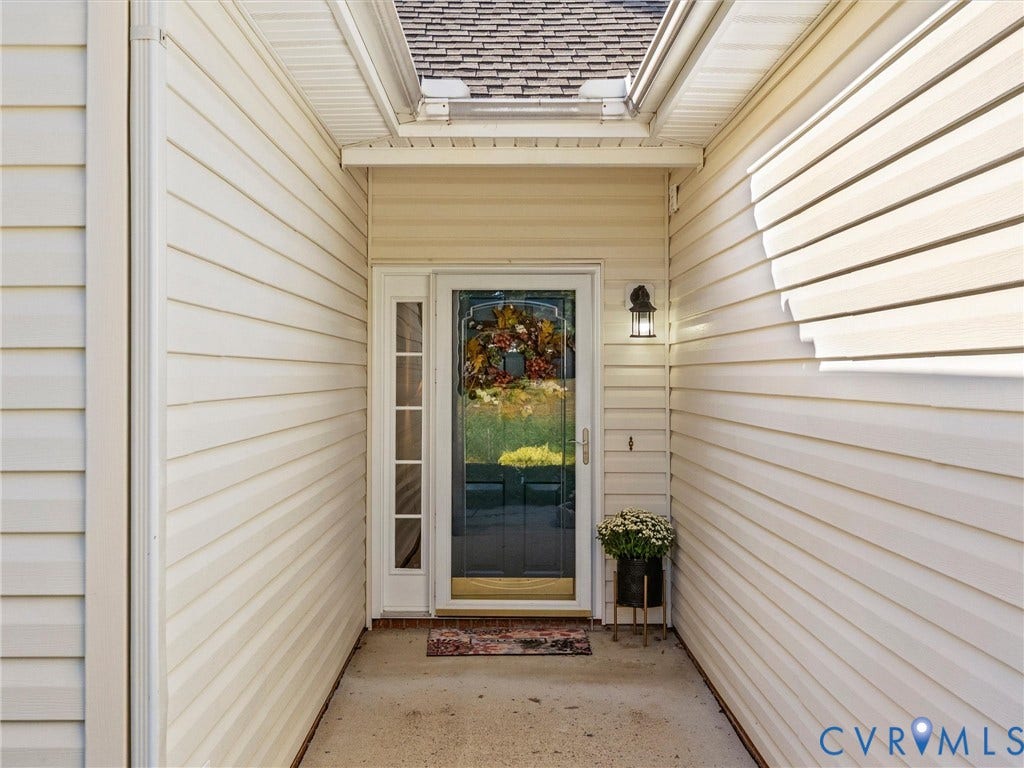 4105 English Holly Circle, Glen Allen, VA 23294 Covered entryway featuring light-colored horizontal siding, a glass-panel door with sidelight, and an attached exterior wall-mounted light fixture