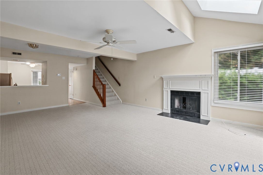 1415 Sycamore Mews Circle, Sycamore Mews, Midlothian, VA 23113 Vaulted ceiling featuring a skylight, fireplace with a decorative mantel and hearth, and a staircase with a wooden handrail