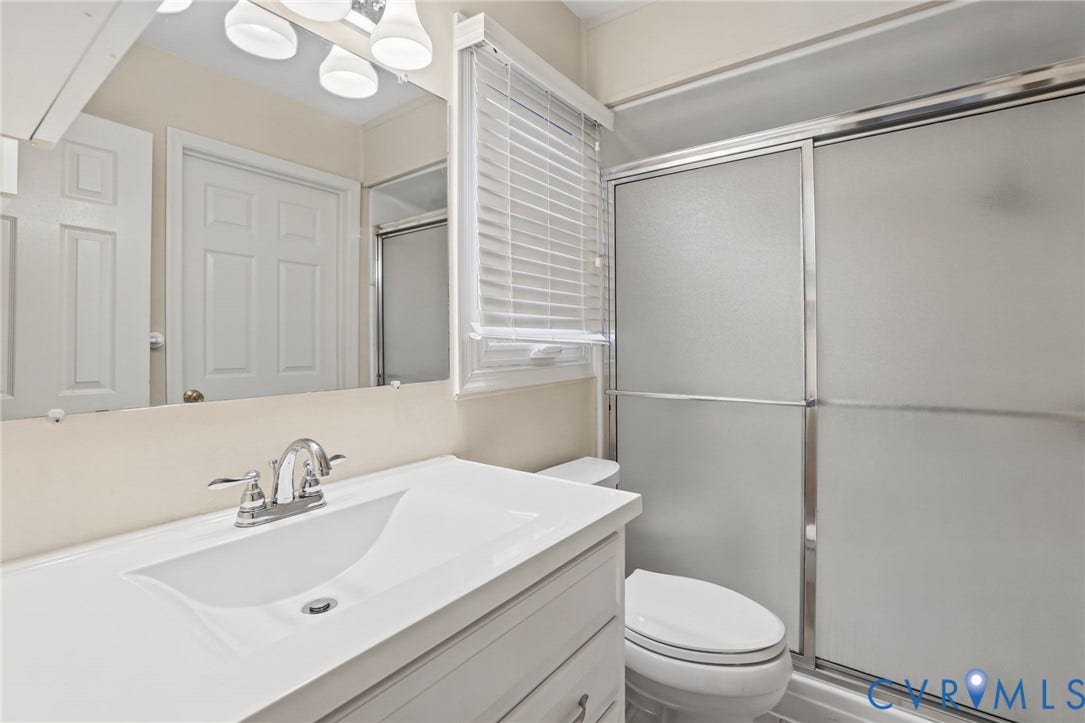 1415 Sycamore Mews Circle, Sycamore Mews, Midlothian, VA 23113 Bathroom featuring a white vanity with an integrated sink, polished chrome faucet, full-width mirror, and a walk-in shower with frosted sliding glass doors