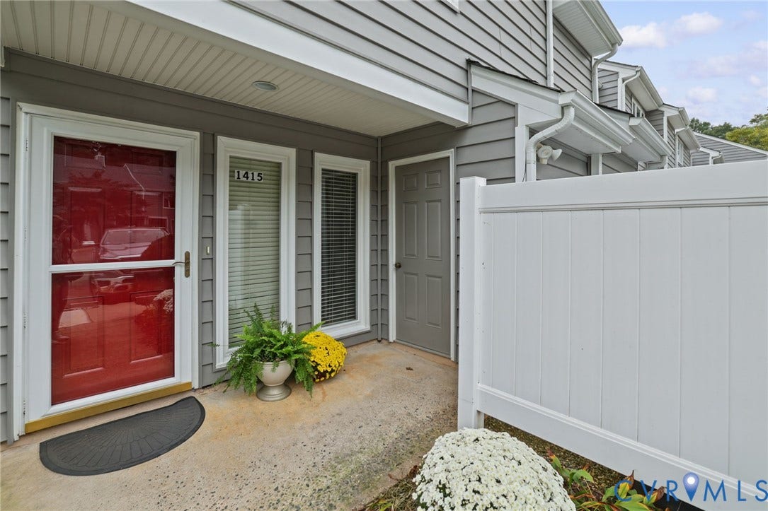 1415 Sycamore Mews Circle, Sycamore Mews, Midlothian, VA 23113 Covered entryway featuring gray horizontal lap siding, a red front door with a glass storm door, dual vertical windows, and a white privacy fence