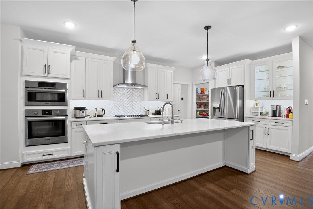 Glen Allen, VA 23059 Kitchen featuring white shaker-style cabinetry, quartz countertops, a herringbone tile backsplash, stainless steel built-in appliances, and a central island with pendant lighting
