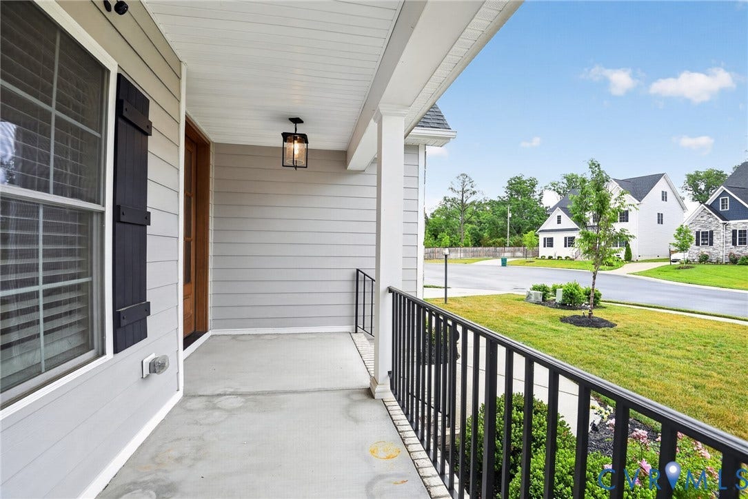 Glen Allen, VA 23059 Covered front porch featuring horizontal lap siding, dark decorative window shutters, a black metal railing, and a pendant-style light fixture