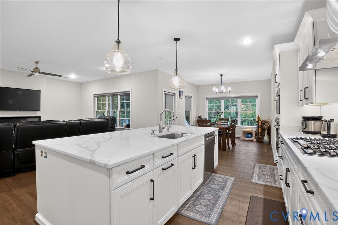 Glen Allen, VA 23059 Kitchen featuring a central island with a solid-surface countertop, white cabinetry with matte black hardware, recessed lighting, and wood-finish flooring