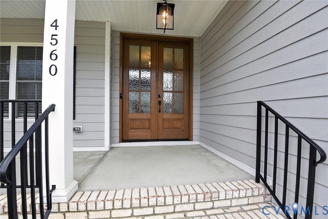 Glen Allen, VA 23059 Covered front porch featuring wood-finish double entry doors with glass panels, light-gray horizontal siding, brick-base steps, and a black metal handrail