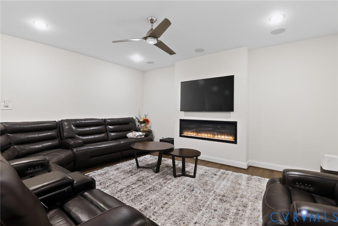 Glen Allen, VA 23059 Living space featuring a linear electric fireplace, built-in television mount, recessed lighting, and a multi-blade ceiling fan