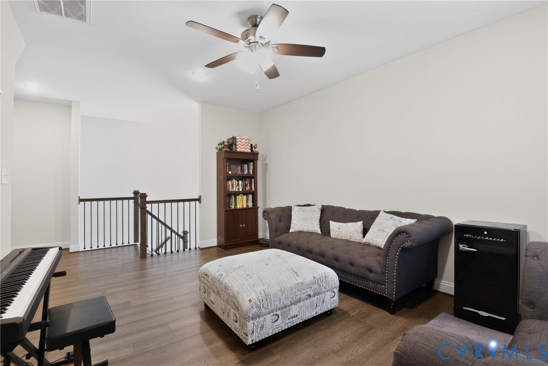 Glen Allen, VA 23059 Open-concept area featuring wood-finish flooring, vaulted ceiling, and a central ceiling fan with integrated lighting, finished with a dark-stained wood baluster railing