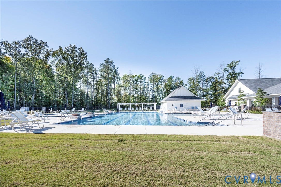 7577 Southamptonshire Way, Autum Pines, New Kent, VA 23124 Outdoor swimming pool featuring a concrete deck, built-in lap lanes, pergola-covered lounge area, and expansive lawn