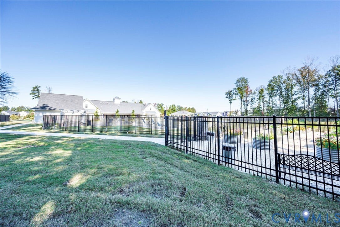 7577 Southamptonshire Way, Autum Pines, New Kent, VA 23124 Fenced outdoor space featuring a graveled area, metal garden planters, and a concrete pathway