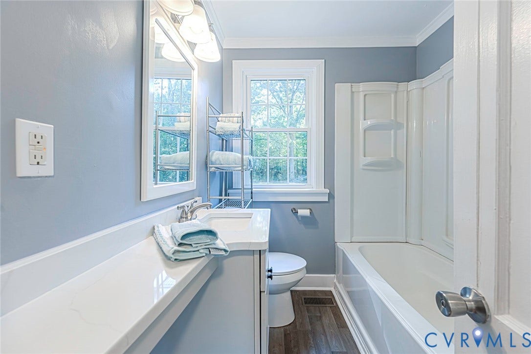 3017 Kingsdale Road, Chesterfield, VA 23237 Bathroom featuring a composite vanity with an integrated sink, polished chrome faucet, multi-light fixture, multi-pane window, and wood-finish flooring