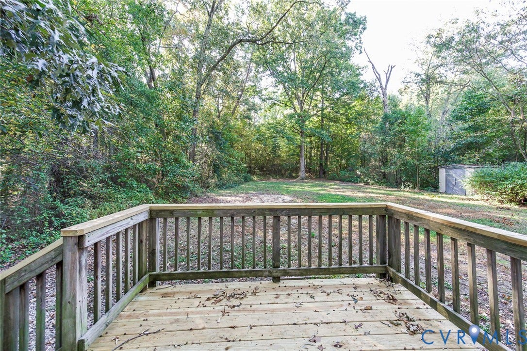 3017 Kingsdale Road, Chesterfield, VA 23237 Wood deck featuring a perimeter railing, overlooking a sprawling yard with mature trees and a detached storage structure