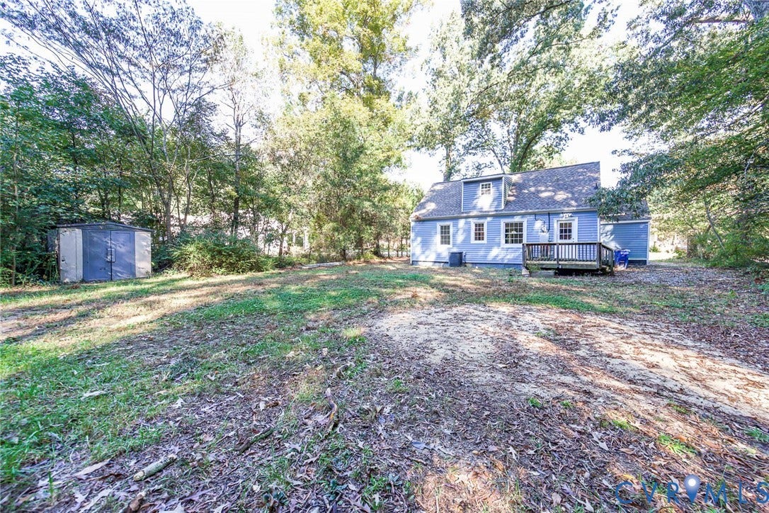 3017 Kingsdale Road, Chesterfield, VA 23237 Exterior view of a two-story residence with blue siding, a shingled roof, a rear wood deck, and a detached storage structure, surrounded by mature trees
