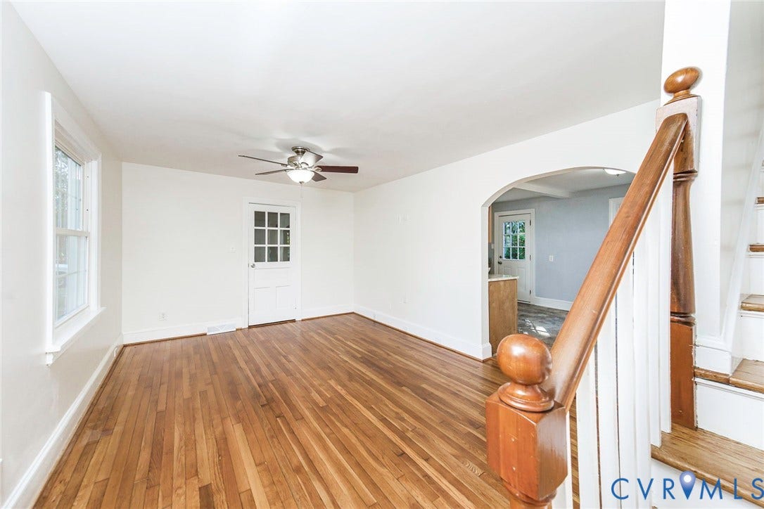 3017 Kingsdale Road, Chesterfield, VA 23237 Living area featuring wood-finish flooring, a ceiling fan with integrated lighting, a glass-paneled exterior door, and an arched entry, complemented by a staircase with a wooden handrail