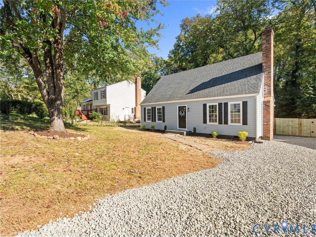 5105 Carryback Drive, Richmond, VA 23234 Cape Cod-style residence featuring horizontal siding, a brick chimney, multi-pane windows with shutters, and a gravel driveway