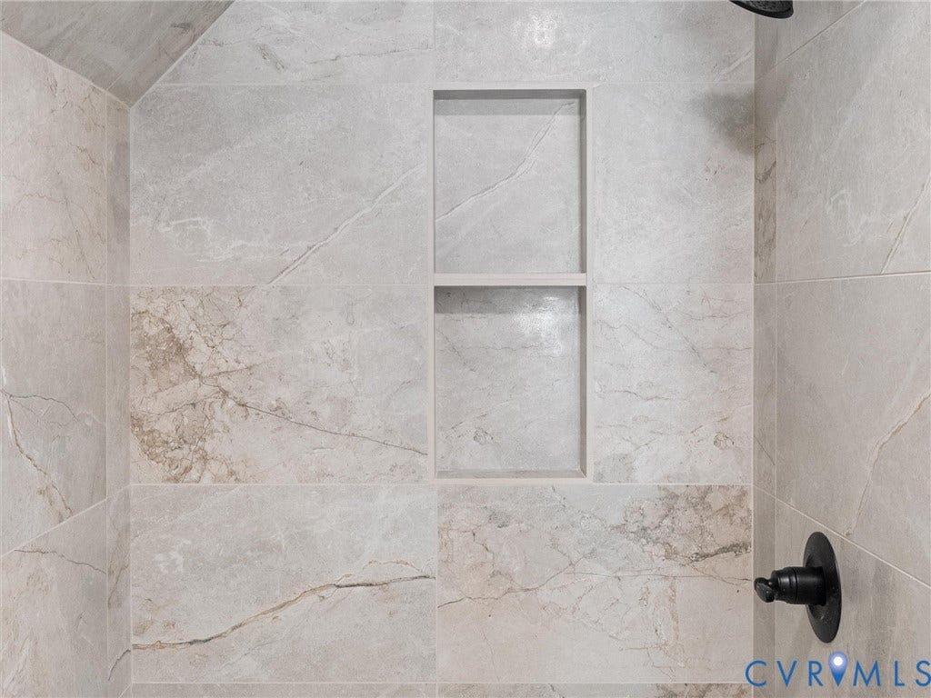 5105 Carryback Drive, Richmond, VA 23234 Shower enclosure featuring large-format neutral-toned tile with veined patterning, built-in dual-shelf recessed niche, and matte black plumbing fixtures