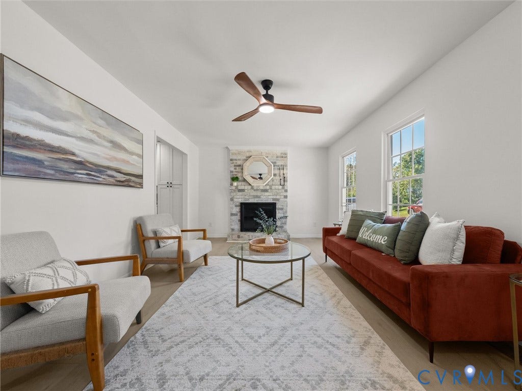 5105 Carryback Drive, Richmond, VA 23234 Living area featuring a floor-to-ceiling stone fireplace, wood-finish flooring, dual-pane windows, and a multi-blade ceiling fan with integrated lighting