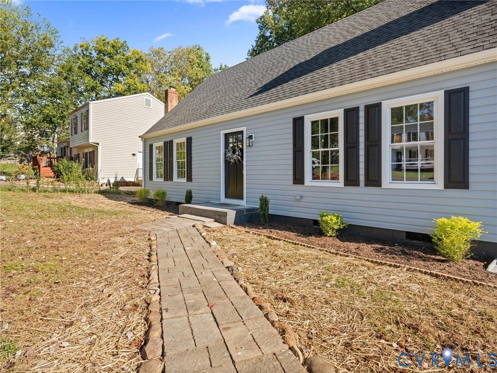 5105 Carryback Drive, Richmond, VA 23234 Light blue vinyl siding exterior featuring dark shutters, a stone paver walkway, multi-pane windows, and an asphalt shingle roof