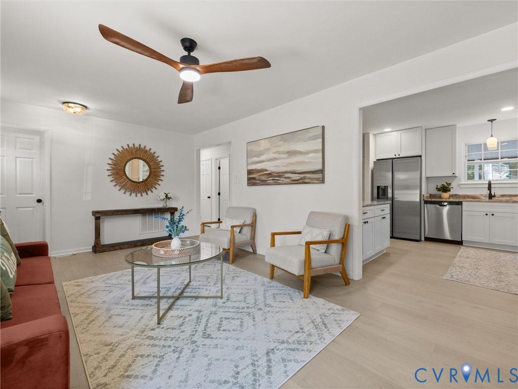 5105 Carryback Drive, Richmond, VA 23234 Open-concept interior featuring light wood-finish flooring, three-blade ceiling fan with integrated lighting, shaker-style kitchen cabinetry, and stainless steel appliances