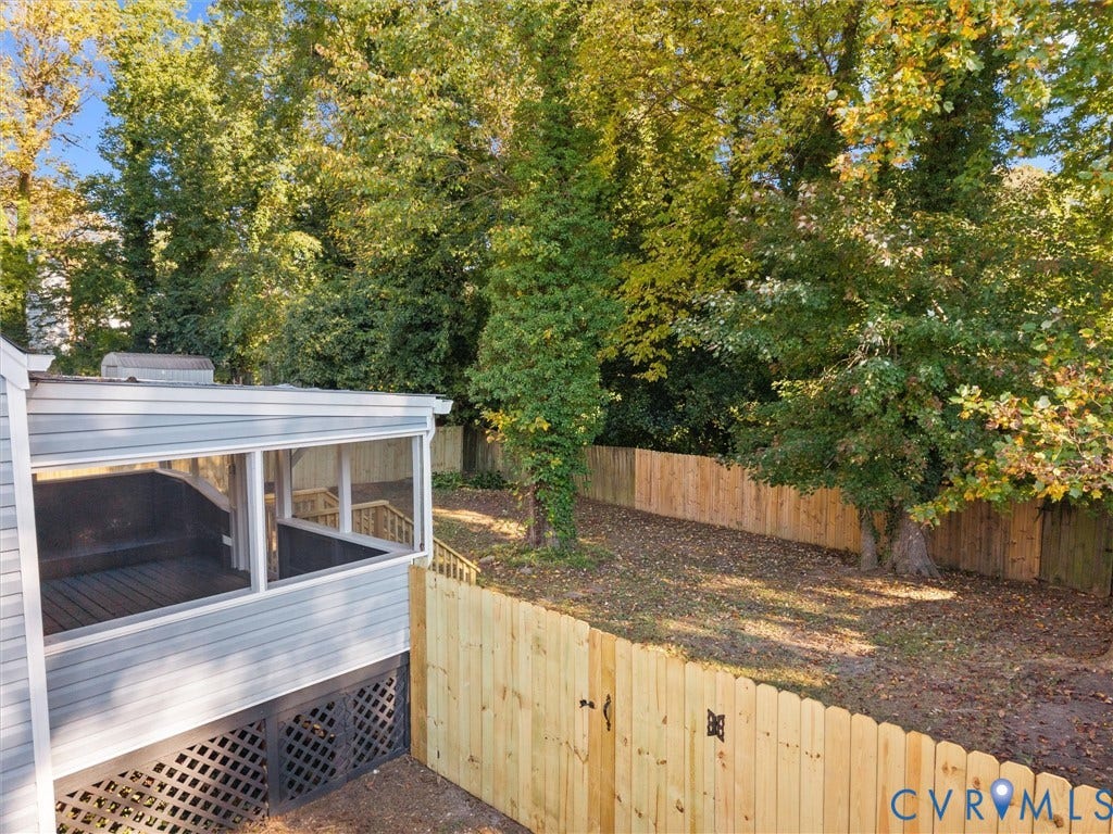 5105 Carryback Drive, Richmond, VA 23234 Enclosed screened porch with vinyl siding, wood-plank deck, and latticework skirting, complemented by a fenced backyard featuring established trees