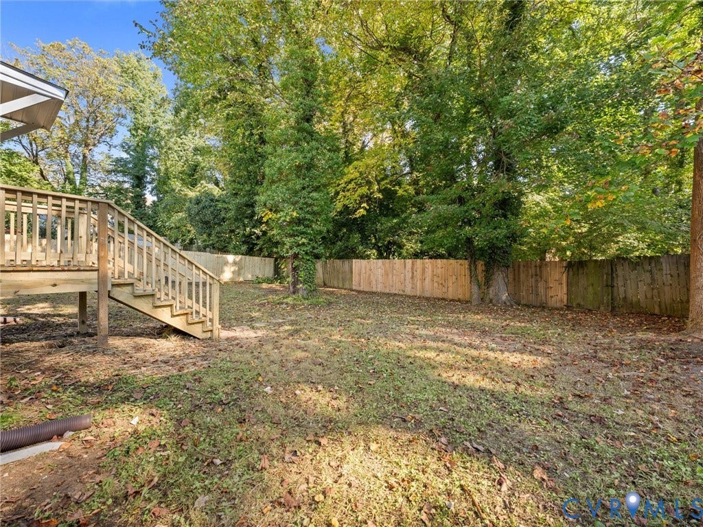 5105 Carryback Drive, Richmond, VA 23234 Rear exterior featuring an elevated wood deck with stairs and a fenced backyard perimeter highlighted by mature trees