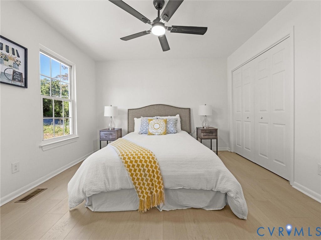 5105 Carryback Drive, Richmond, VA 23234 Bedroom interior featuring light wood-finish flooring, double-panel closet doors, a multi-blade ceiling fan with integrated lighting, and a single-hung window