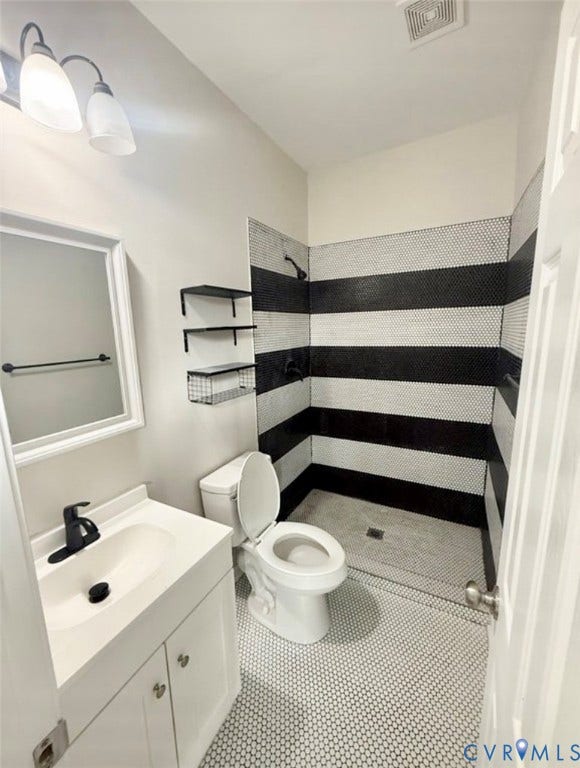 1201 W Broadway, Hopewell, VA 23860 Bathroom featuring a walk-in shower with horizontal black and white tile detailing, penny-round tile flooring, a white vanity cabinet, a wall-mounted medicine cabinet, and matte black hardware