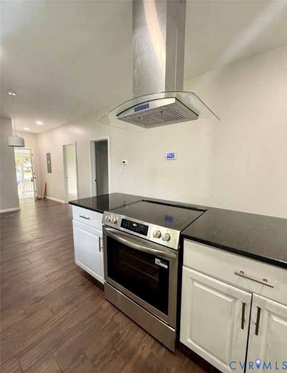 1201 W Broadway, Hopewell, VA 23860 Kitchen featuring stainless steel slide-in range, glass-and-steel chimney range hood, dark solid-surface countertops, white shaker-style cabinetry, and wood-finish flooring