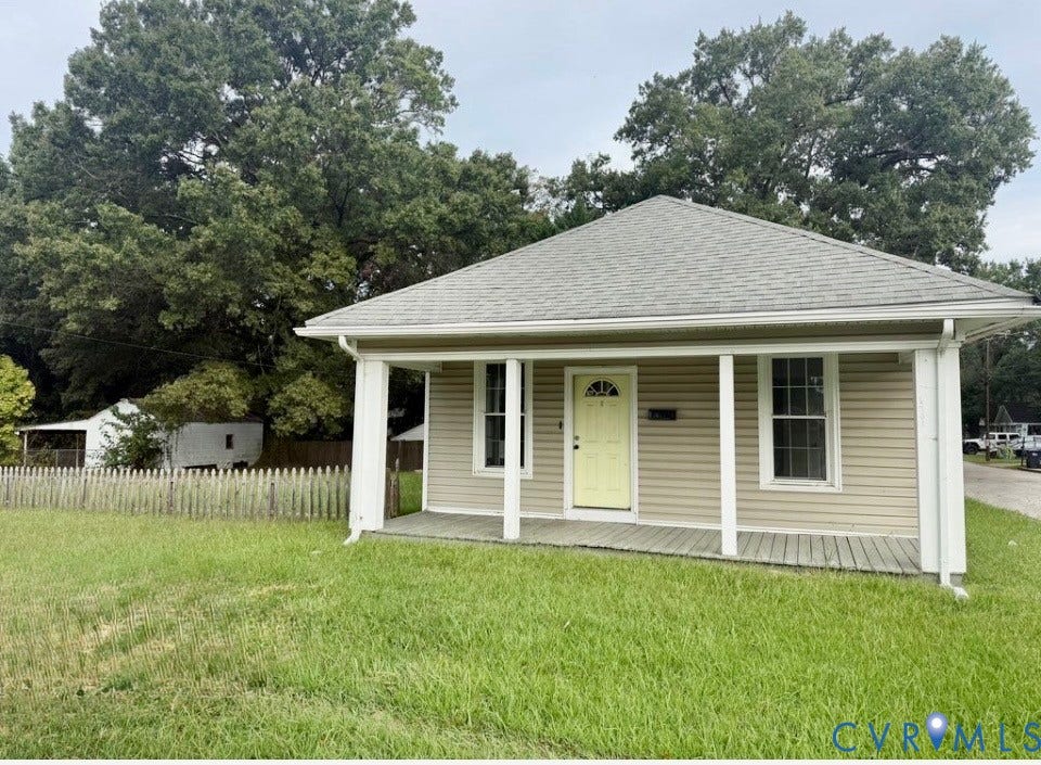 1201 W Broadway, Hopewell, VA 23860 Single-story exterior featuring tan horizontal siding, a covered front porch with support columns, a hipped roof, and a wood-slat perimeter fence