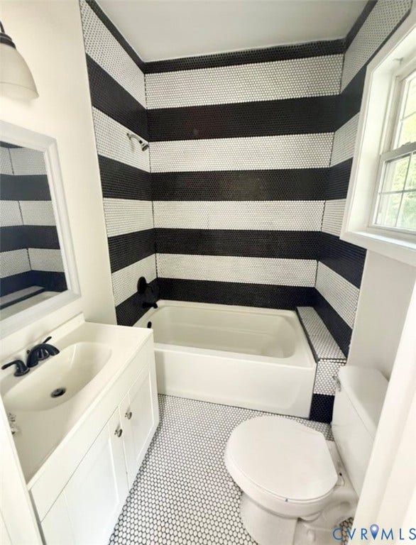 1201 W Broadway, Hopewell, VA 23860 Bathroom featuring horizontal black and white penny tile walls, white vanity with an integrated sink, matte black faucet hardware, and penny tile flooring