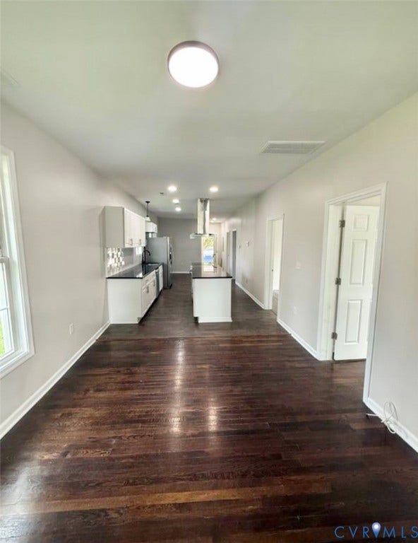 1201 W Broadway, Hopewell, VA 23860 Dark wood-finish flooring, white cabinetry, a center island with a dark countertop, recessed lighting, and a stainless steel range hood