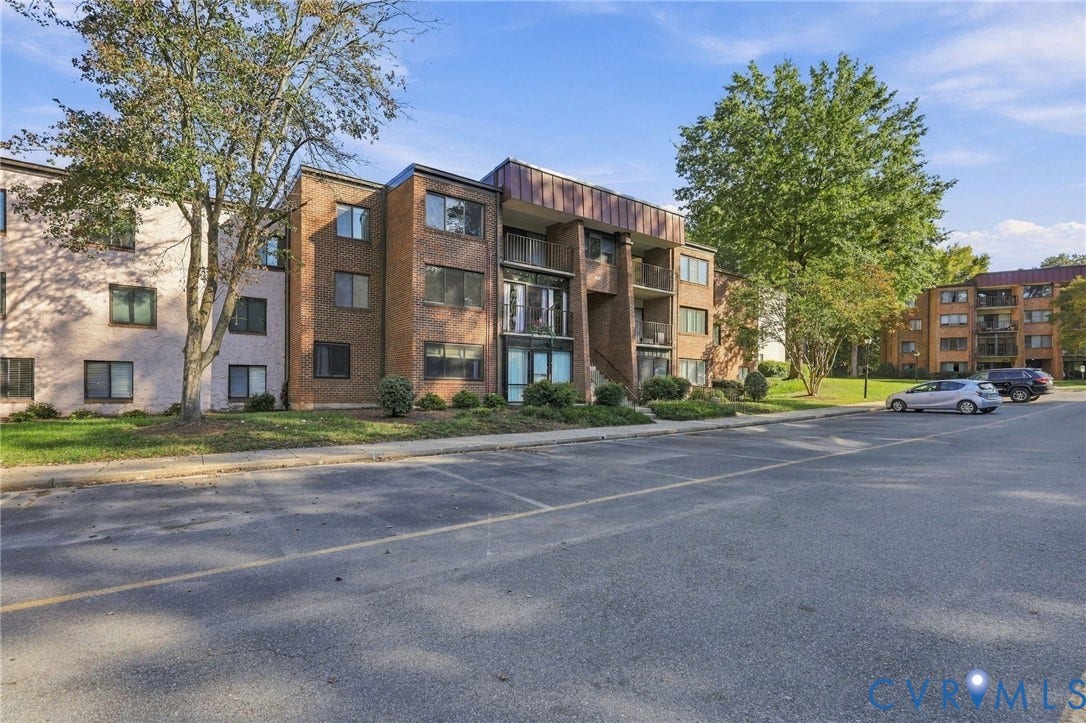 1503 Bronwyn Road, #303, Regency, Henrico, VA 23238 Multi-story brick exterior featuring recessed balconies, metal mansard roof detailing, and paved off-street parking