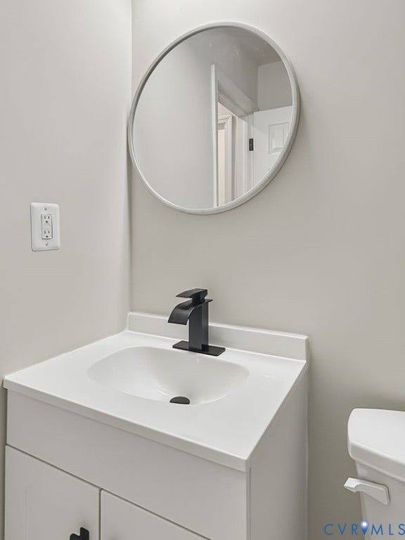 2500 ford Avenue, Richmond, VA 23223 White vanity with an integrated basin, matte black faucet, round mirror, and white toilet