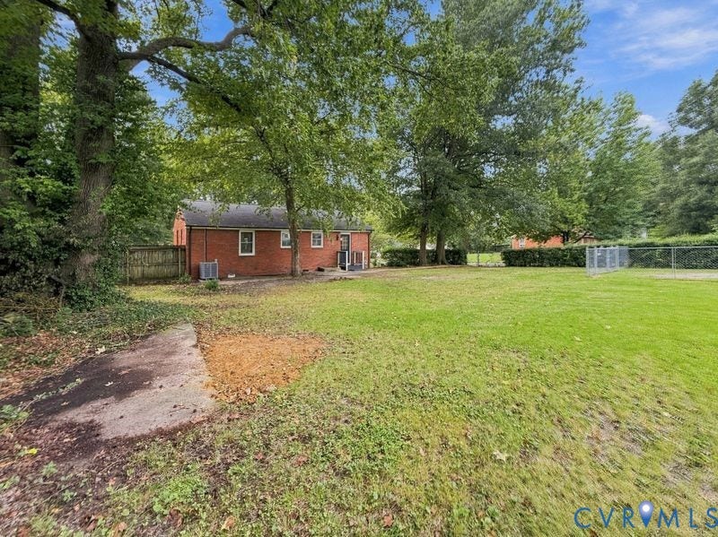 2500 ford Avenue, Richmond, VA 23223 Expansive backyard featuring a brick exterior, mature trees, wood privacy fencing, and metal chain-link perimeter fencing