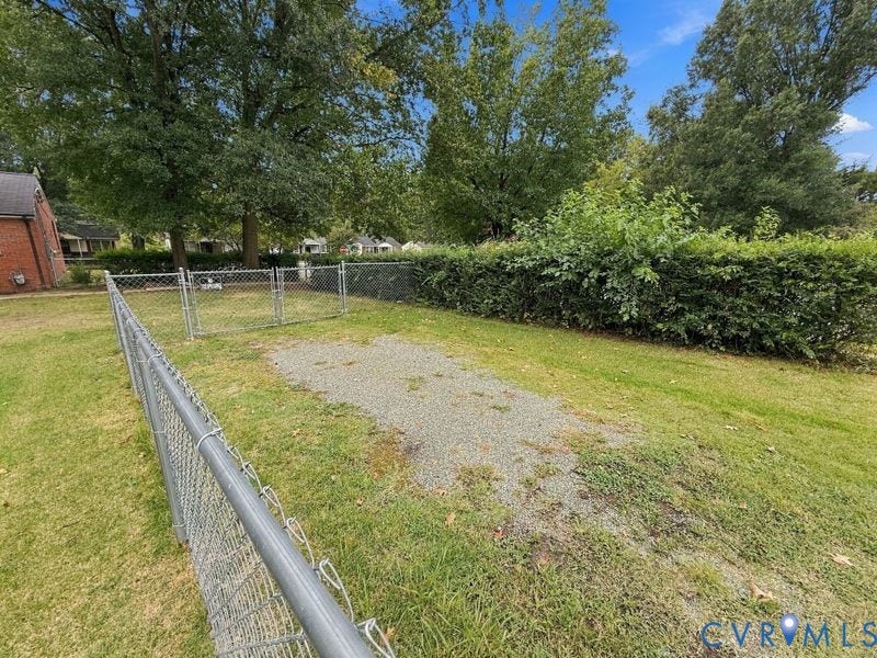 2500 ford Avenue, Richmond, VA 23223 Backyard area featuring chain-link fencing, mature trees, and a manicured hedge perimeter