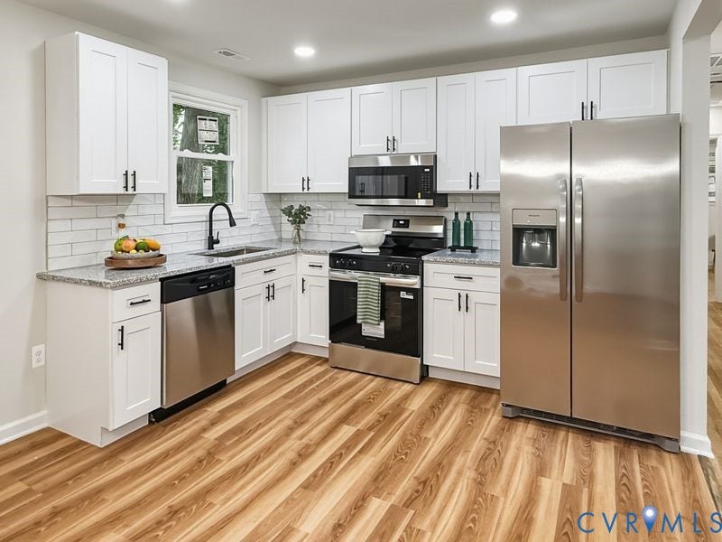 2500 ford Avenue, Richmond, VA 23223 Kitchen featuring white shaker-style cabinetry, stone-finish countertops, subway tile backsplash, stainless steel appliances, and wood-finish flooring