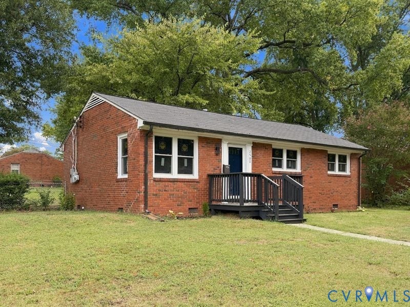 2500 ford Avenue, Richmond, VA 23223 Exterior brick facade featuring a dark-toned wooden porch, crisp white trim, and a gabled roof set on a lot with mature trees