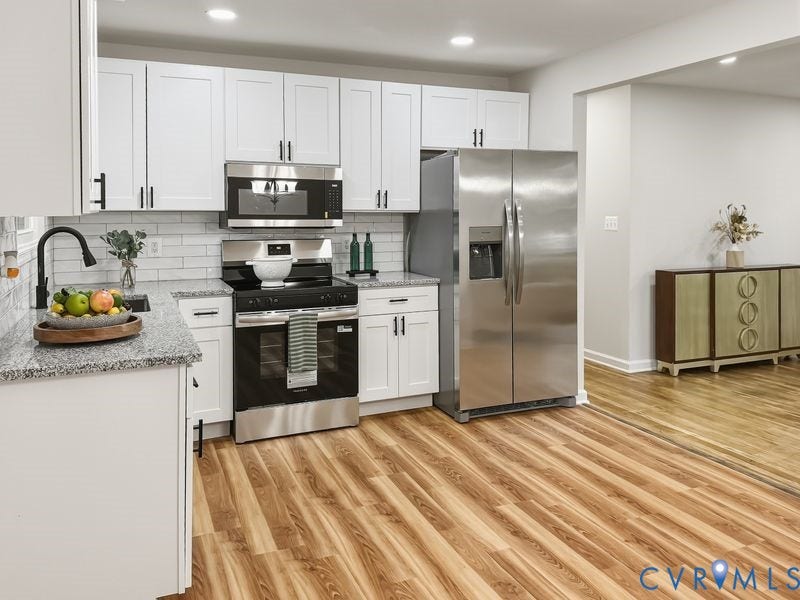 2500 ford Avenue, Richmond, VA 23223 Kitchen featuring white shaker-style cabinetry, stone-finish countertops, subway tile backsplash, stainless steel appliances, and wood-finish flooring