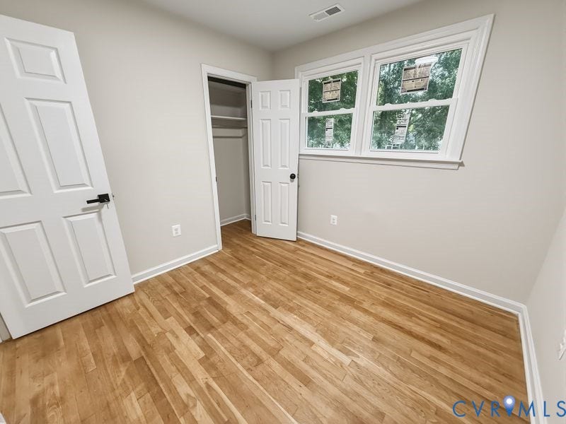 2500 ford Avenue, Richmond, VA 23223 Room featuring wood-finish flooring, six-panel interior doors, neutral wall paint, and a built-in closet with overhead shelving