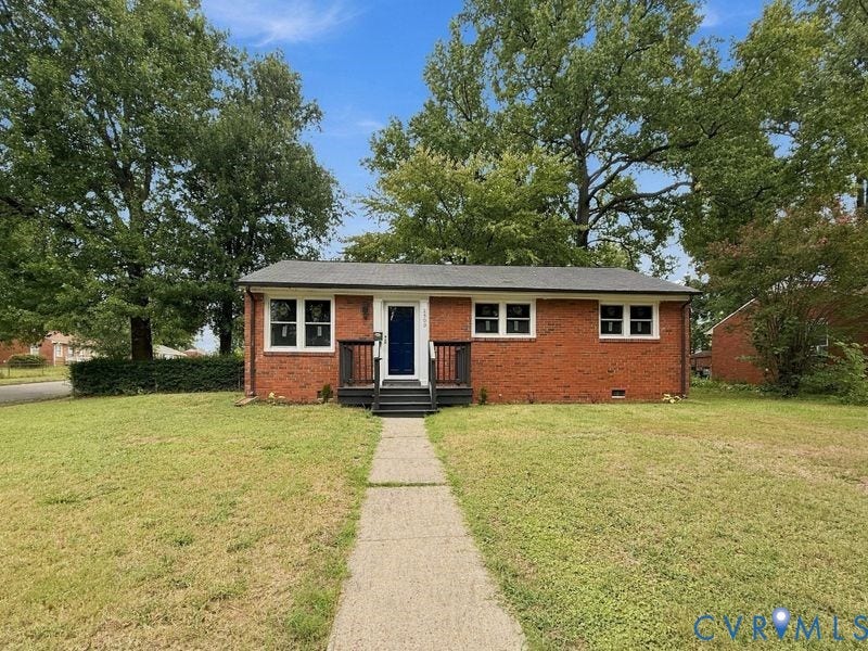 2500 ford Avenue, Richmond, VA 23223 Single-story brick exterior featuring a covered front entry with dark-finished railings, a concrete walkway, and mature trees on the lot
