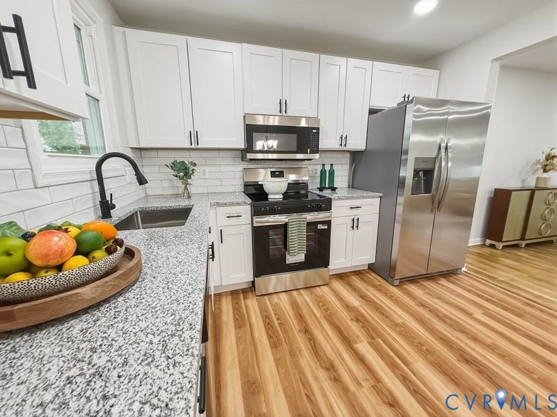 2500 ford Avenue, Richmond, VA 23223 Kitchen featuring white shaker-style cabinetry, stone-finish countertops, subway tile backsplash, stainless steel appliances, and wood-finish flooring