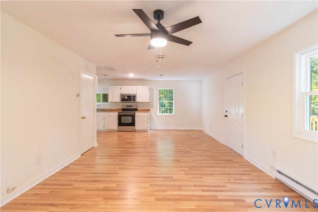 9045 Blounts Corner Road, Smithfield, VA 23430 Wood-finish flooring throughout, matte black ceiling fan with integrated lighting, white cabinetry, and stainless steel appliances