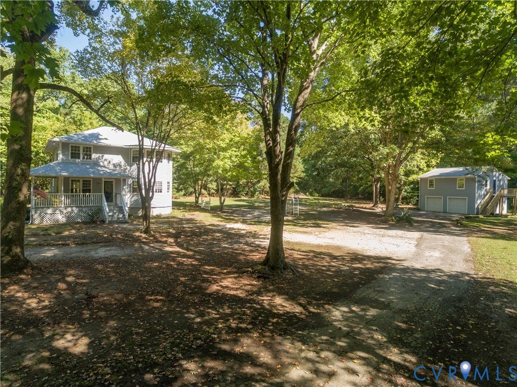 9045 Blounts Corner Road, Smithfield, VA 23430 Two-story home with a wrap-around porch, detached two-car garage, expansive grounds with mature trees, and a paved driveway