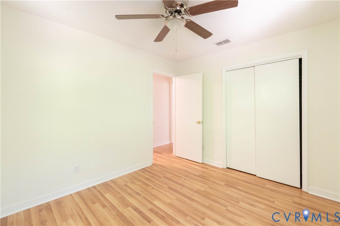 9045 Blounts Corner Road, Smithfield, VA 23430 Neutral-toned room featuring wood-finish flooring, a ceiling fan with integrated lighting, and a dual-panel sliding closet