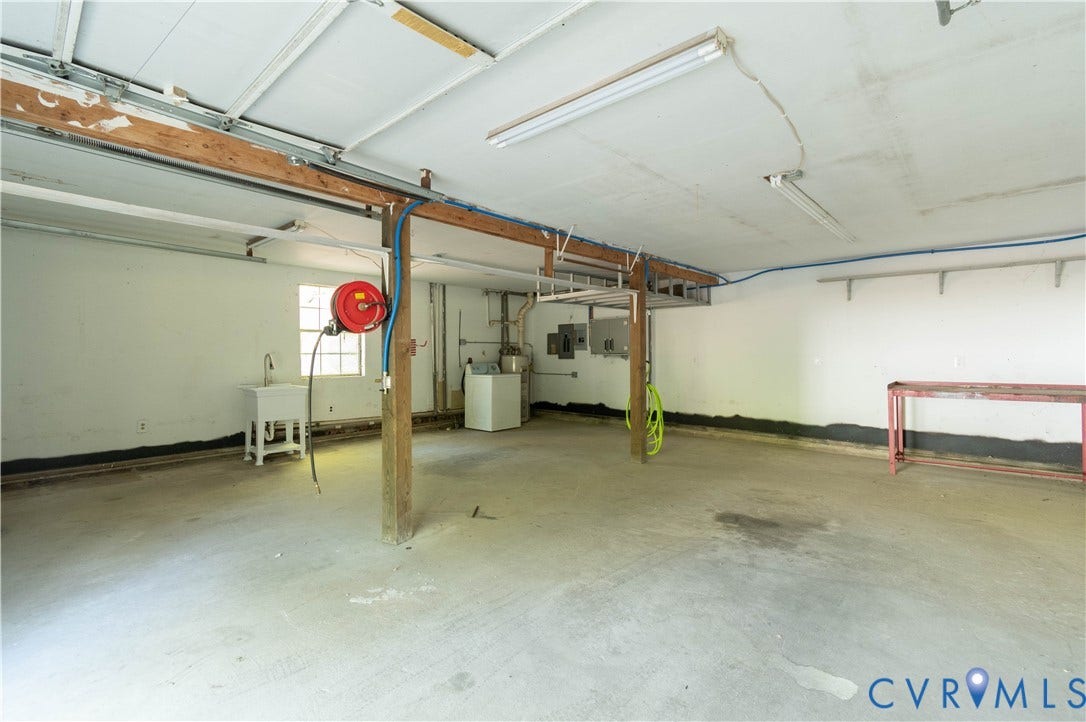 9045 Blounts Corner Road, Smithfield, VA 23430 Multi-car garage featuring a concrete floor, built-in utility sink, exposed wood support beams, and overhead fluorescent lighting