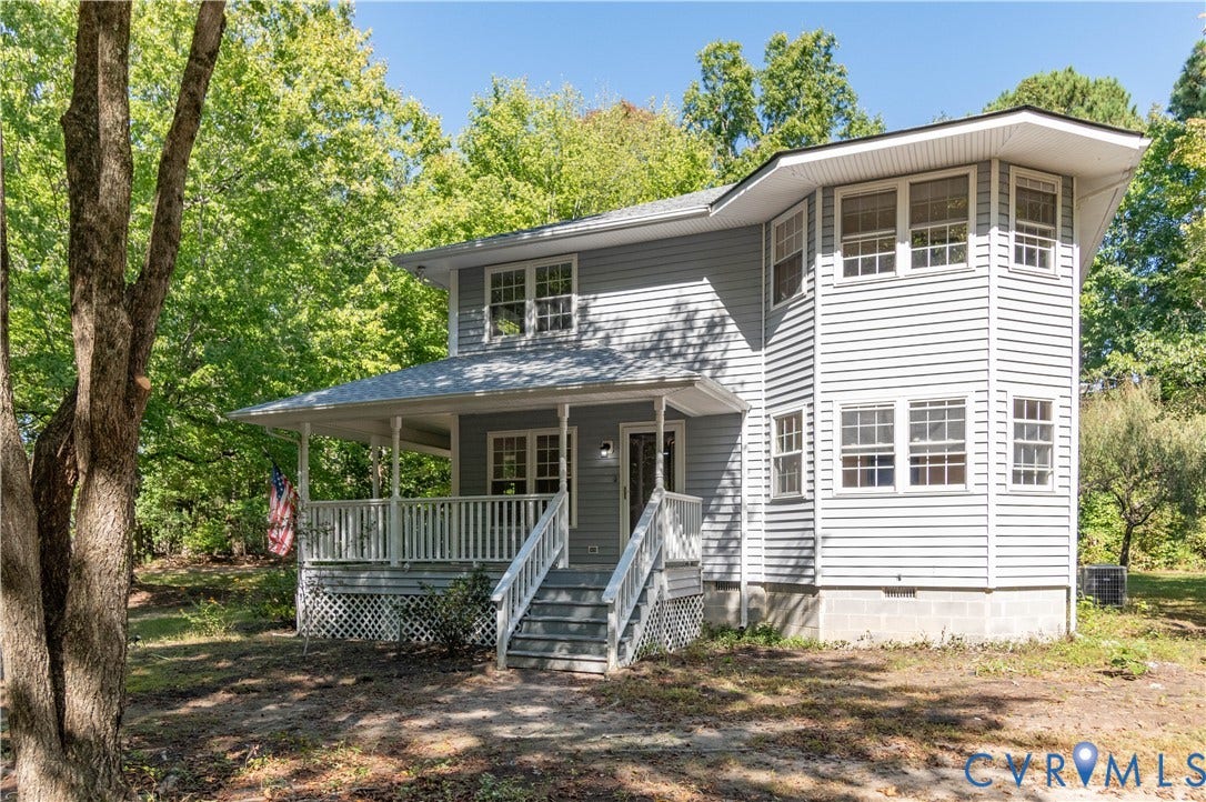 9045 Blounts Corner Road, Smithfield, VA 23430 Two-story home featuring gray vinyl siding, a wrap-around front porch with white railing, a hexagonal turret architectural element, and a metal lattice foundation skirt