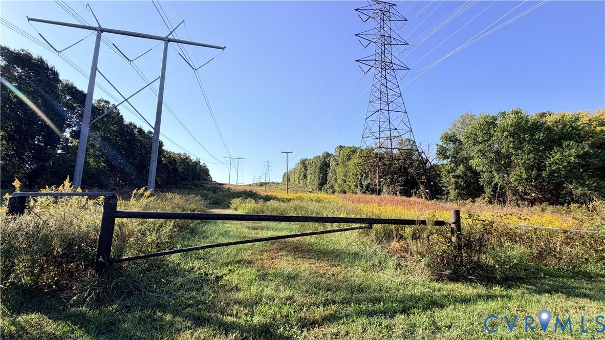 16080 Neabsco Road, Neabsco, Woodbridge, VA 22191 Expansive open land parcel featuring a metal swing-gate entry, natural vegetation, and mature perimeter trees