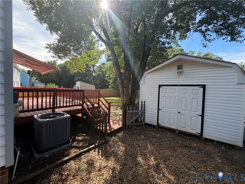 2228 Early Settlers Road, Midlothian, VA 23235 Raised wood deck with integrated railings, detached storage shed with white vinyl siding, and mature tree-lined grounds