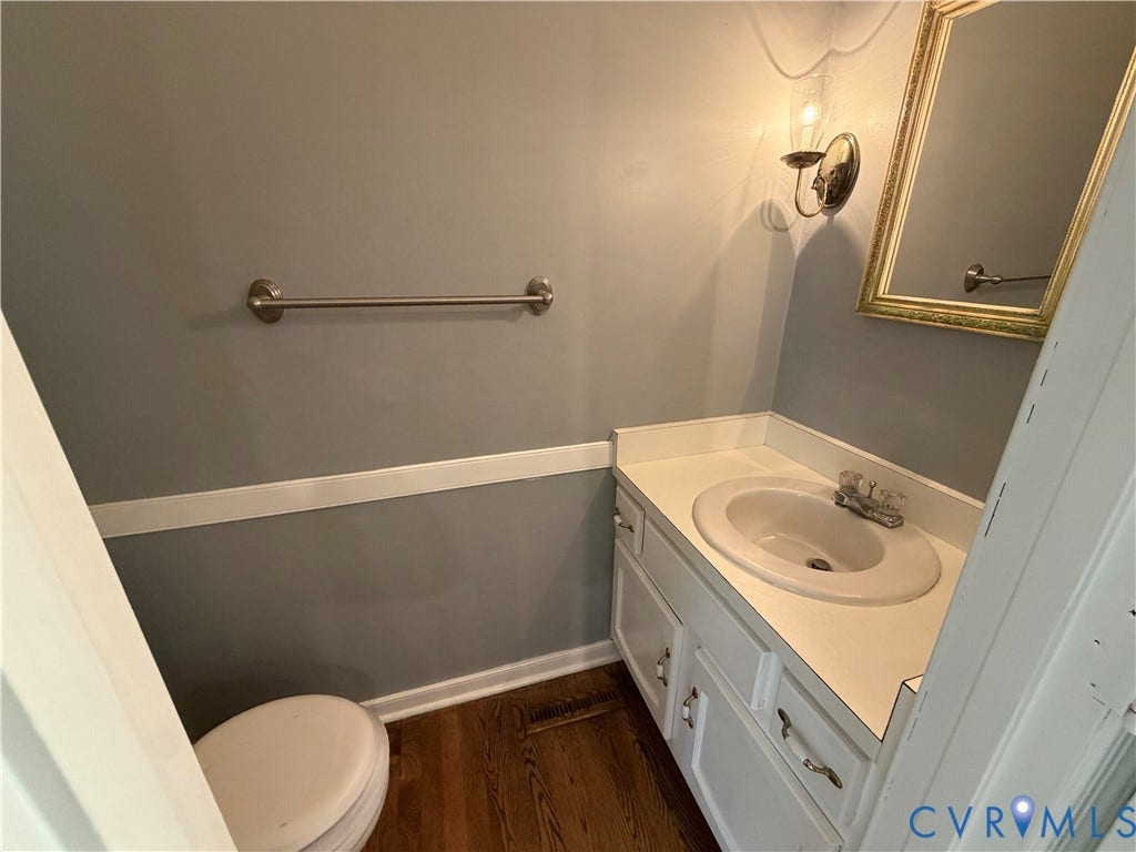 2228 Early Settlers Road, Midlothian, VA 23235 Powder room featuring wood-finish flooring, white cabinetry with integrated countertop, wall-mounted light fixture, and horizontal chair rail molding
